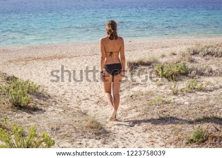 Back view of caucasian female walking on the beach