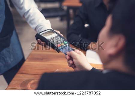 Businessman paying by credit card with a credit card reader machine in a restaurant

