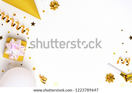 Holiday frame or background with balloon, gift, confetti, golden star, carnival cap and streamer. Flat lay style. Birthday or party greeting card with copy space.
