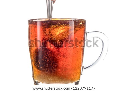 Dissolving a piece of sugar in tea in a transparent mug on a white background, a storm in a glass