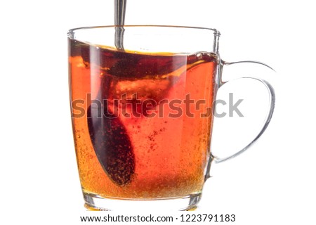 Dissolving a piece of sugar in tea in a transparent mug on a white background, a storm in a glass