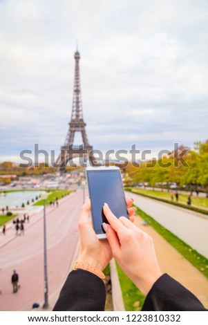 Girl using cellphone with Paris city background and Eiffel tower.