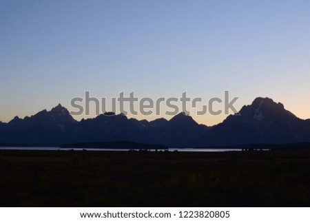 Beautiful sunset behind the iconic Grand Teton Mountains with mountain silhouettes and sun aura at the Grand Teton National Park, USA
