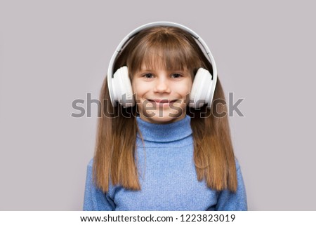 Happy smiling child enjoys listens to music in headphones over white background