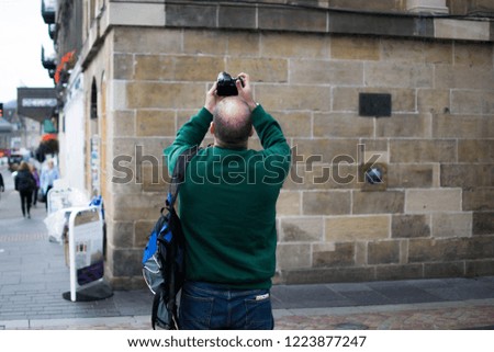 Mid-aged man taking photos to an historical building.