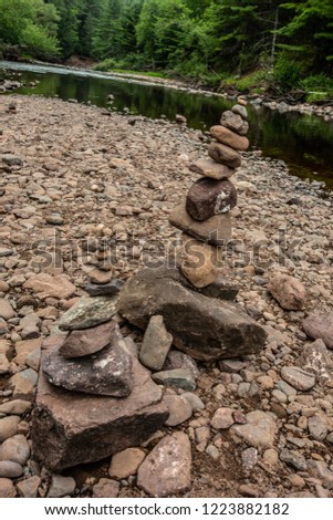stacked rocks on the shoreline of a river flowing through a northern wisconsin state park.