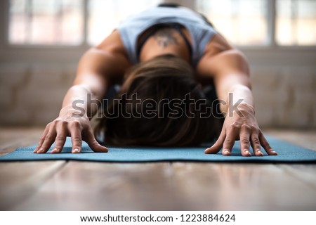 Young sporty attractive woman practicing yoga, doing Child exercise, Balasana pose, working out, wearing sportswear, indoor close up, at yoga studio or at home. Well being concept Royalty-Free Stock Photo #1223884624