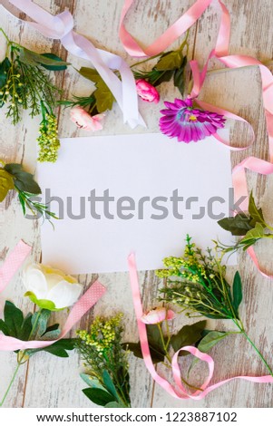 Flat lay with white sheet and pink flowers and pink satin ribbons on wooden background top view toned picture