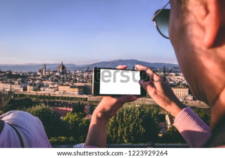 Old tourist woman taking photo picture with her phone of the Florence city old town duomo cathedral Santa Maria del Fiore on the background panorama view from square Piazzale Michelangelo, 