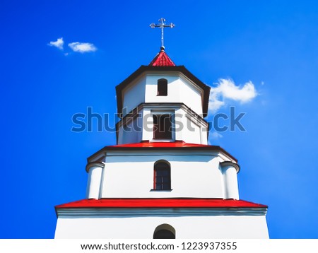Catholic Church of the Nativity of the Theotokos. Borisov, Belarus. The upper part of the building with a cross against the blue sky with white clouds.