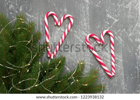 Winter background with fir branches, garland and candy canes on a gray concrete background. Greeting card.