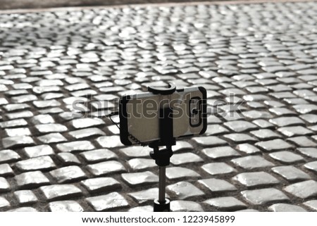 Mobile phone on stand over concrete block floor in sunny reflection