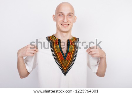 bald guy in the national African costume-dashiki. emotional portrait of a student. smiling male animator posing on white background. clothes for party and fashion show