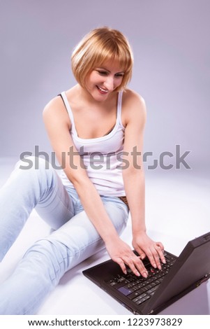 Youth Lifestyle Ideas and Concepts. Tranqiul Caucasian Blond Woman Posing With Laptop Against White Backgound. Sitting on Floor. Vertical Shot