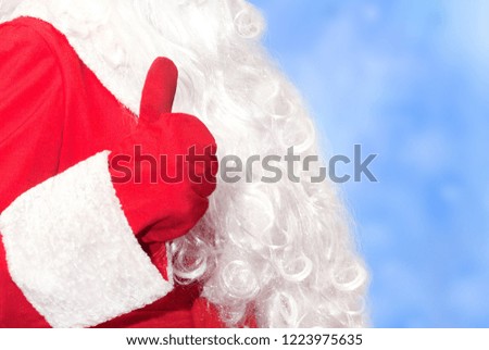 Santa Claus hand shows thumbs up on blue frosty background