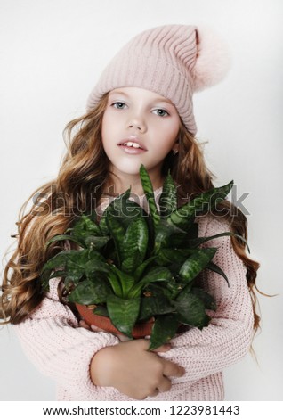 Beauty and fashion concept: Little girl wearing pink outfit and holding flower, close up