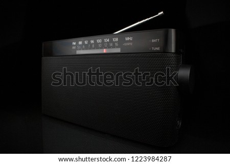 Modern portable fm radio receiver on glass black table and black background. Isolated object close-up photo.