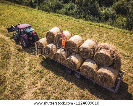 Aerial Drone Photo of Farmer Harvesting Hay Rolls in the Wheat Field with a Red Tractor - Sunny Summer Day, Vintage Look Edit