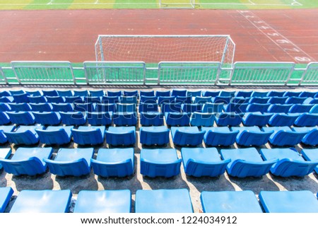 Plastic seats on the stands around the school's open-air football field, overlooking from the back