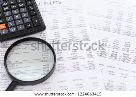 accounting audit concept. calculator and magnifying glass on financial statement and balance sheet annual. Royalty-Free Stock Photo #1224063415
