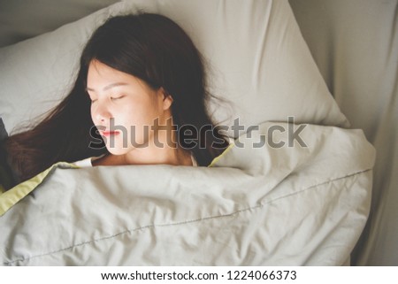 Bird’s-eye view image of a woman  sleeping with gray pillow and blanket.