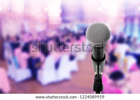 Microphone on boom stand ready for the meeting ,blurred background group of people sitting around table. Microphone on stage in conference hall.