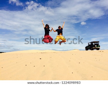Young tourist jumping on the white sand dunes in Mui ne, Vietnam.holiday travel vacation adventure concept