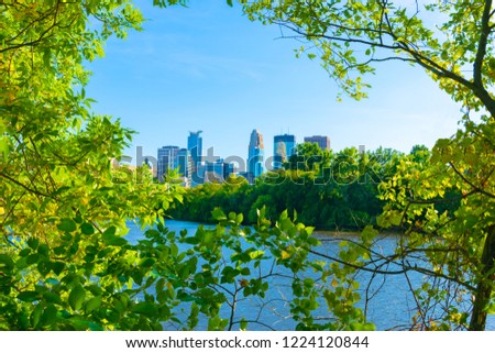 Downtown Minneapolis and Mississippi river through  green leafs trees branches   
