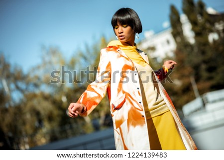 Brightly painted eyes. Brunet stylish girl dancing on empty street while participating in photo shoot