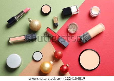 Flat lay composition with makeup products and Christmas decor on color background