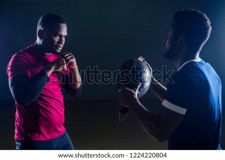 team work two handsome african american sportsman in boxing on a black background in the gym,trainer and ward practicing boxing