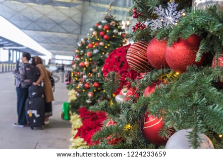 Christmas decoration in airport. Outside departure zone in Hong Kong International Airport. Christmas trees in line decorated with balls, snowflakes and garlands. Unrecognizable people on background. Royalty-Free Stock Photo #1224233659
