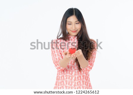 Photo of asian curious woman in red dress rejoicing her birthday or new year. Young woman holding red heart being excited and surprised  holiday present isolated white background