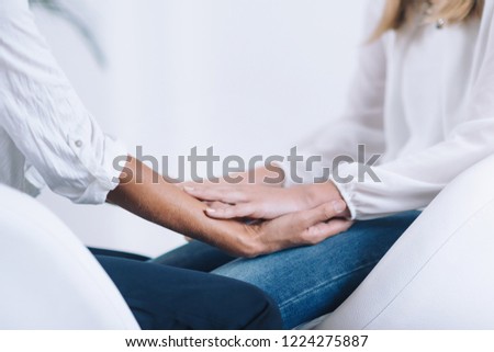 Female Theta healing therapist performing alternative therapy treatment with young woman patient. Therapist holding hands and transfer energy. Wearing white clothes. Royalty-Free Stock Photo #1224275887
