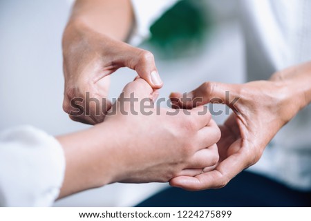 Close up horizontal image of female hands performing muscle testing at Theta healing session. Therapist and patient sitting and wearing white clothes. Energy healing concept Royalty-Free Stock Photo #1224275899