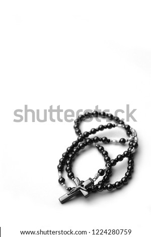 black and white image of rosary beads against a stark white background