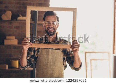 Closeup photo picture portrait of funky positive cheerful satisfied with toothy smile glad optimistic constructor foreman guy engineer holding large big frame in hands looking at camera