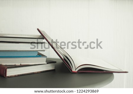 Stack of books on the table, opened book on side with white background