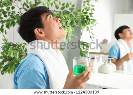 Man rinsing mouth with mouthwash in bathroom. Teeth care Royalty-Free Stock Photo #1224300139