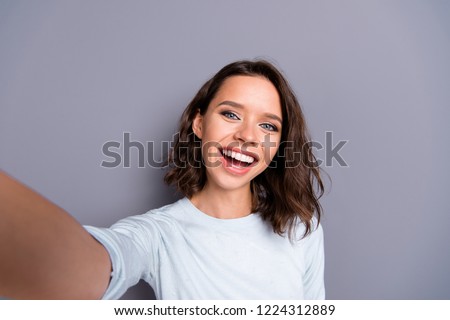 Lady blogger with her brunette hair she take picture on cellular make wide toothy smile isolated on gray background
