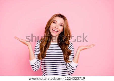 Positive lady in striped clothes casual outfit with her brown wave hairdo she hold on hand palm invisible object product indicate novelty idea or decision isolated on pastel pink background