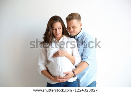 Pregnant woman with her husband on white background. Happy young family