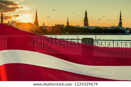 Conceptual collage image symbolizing 100 years of Latvian State Independence.  Ancient buildings of Riga - the capital of Latvia known by unique Gothis architecture, Flag of Latvia as background