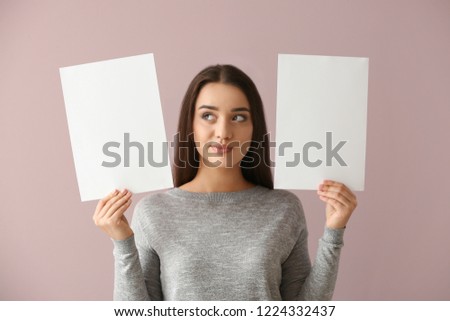 Thoughtful young woman with blank sheets of paper on color background