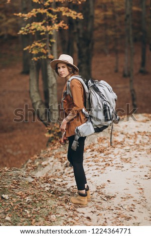 woman traveler with backpack holding hat and looking at amazing forest, travel concept, space for text, atmospheric epic moment
