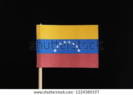 A official and original flag of Venezuela  on toothpick on black background. A horizontal tricolor of yellow, blue and red with an arc of eight white five pointed stars centered on the blue band.