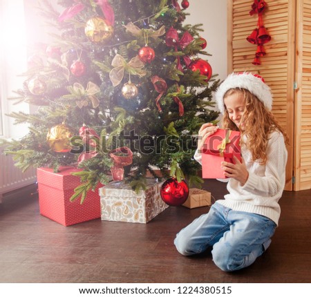 Child with gift near christmas tree. Girl at home. New year!