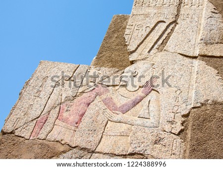 The wall of the ancient Egyptian temple of Karnak (founded 3500 years BC) with hieroglyphs carved on it and figures of pharaoh and god.