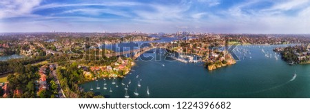 Elevated wide panorama over Greater Sydney area from Inner West along wide winding Parramatta river over Gladesville bridge with local residential suburbs on shores. Royalty-Free Stock Photo #1224396682
