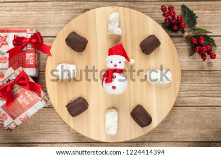 typical Spanish almond and chocolate polvorón with Santa, Christmas presents and mistletoe on wood table from above 